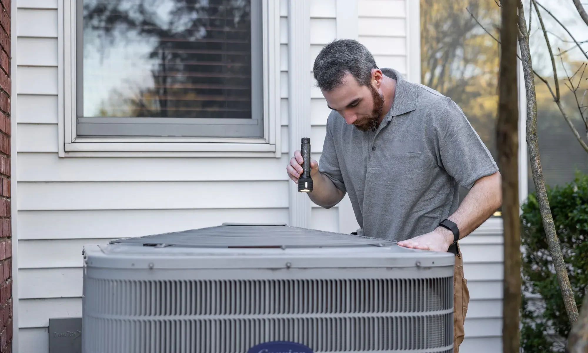 An outdoor heat pump unit beside a home during a Northwest Indiana winter.