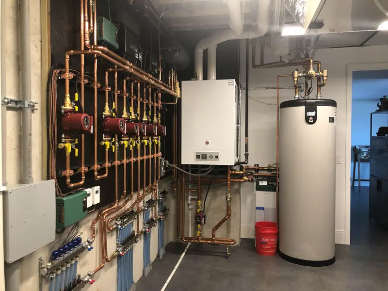 Finished basement mechanical room with a wall-hung boiler, indirect hot water tank, and neatly run copper piping.
