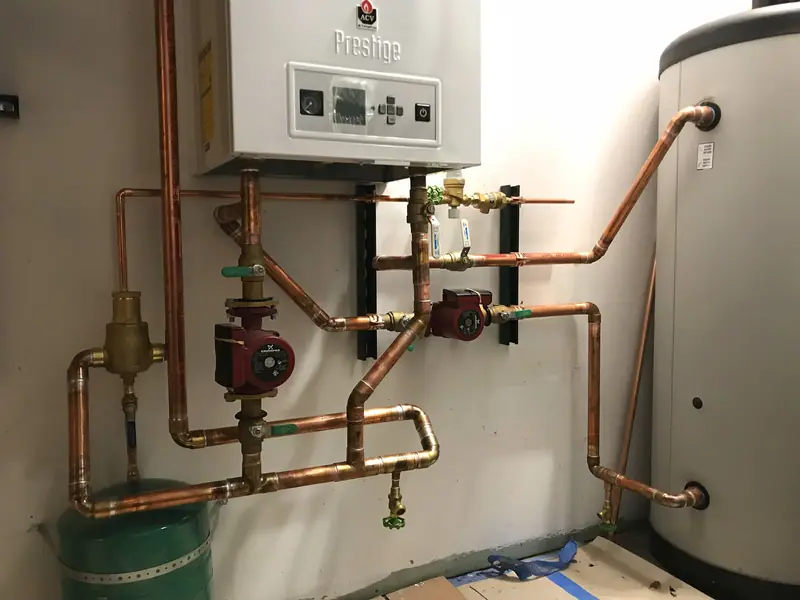Large copper-piped boiler system with six circulator pumps feeding four radiant floor manifolds.
