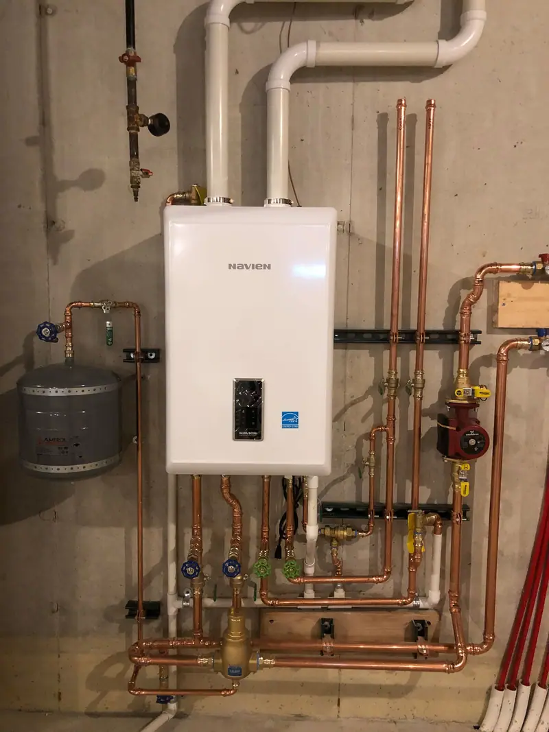 Navien wall-hung condensing boiler with copper supply and return piping and an expansion tank.
