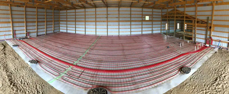 Radiant PEX loops tied to reinforcing mesh over a vapor barrier, ready for a concrete slab.