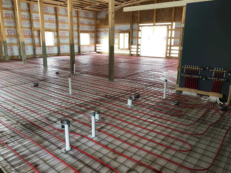 In-floor radiant tubing and a wall-mounted manifold in a home under construction.