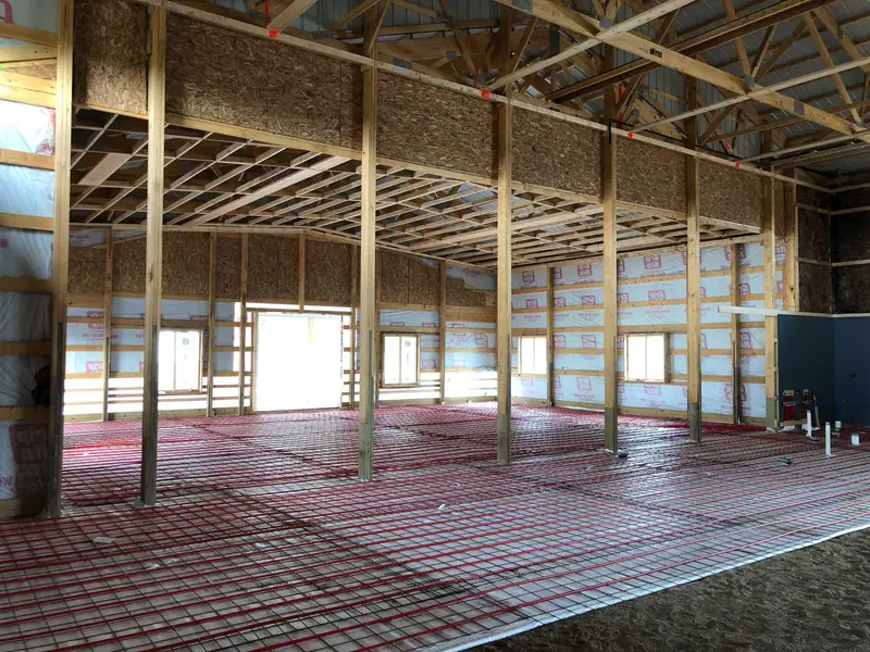 Radiant floor tubing over rebar inside a wood-framed home during construction.