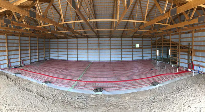 Panorama of a pole-barn floor fully covered with radiant heating tubing over reinforcing mesh.