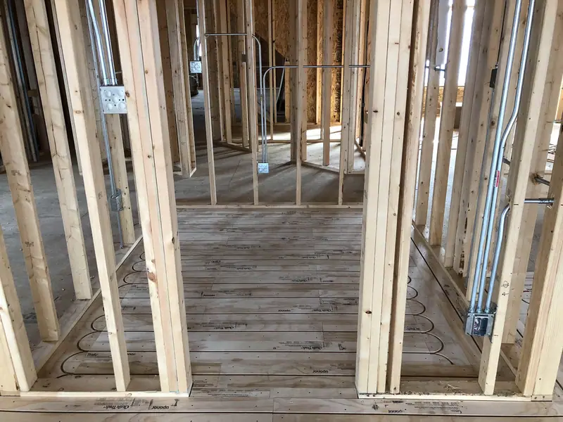 Radiant subfloor tubing routed through door openings between framed rooms.